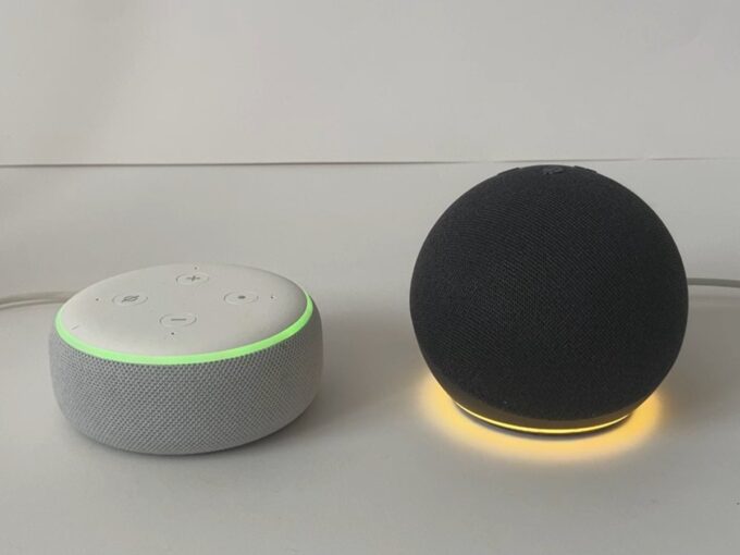 Echo Dot 5th gen glowing yellow and Echo Dot 3rd gen glowing yellow-green for a notification